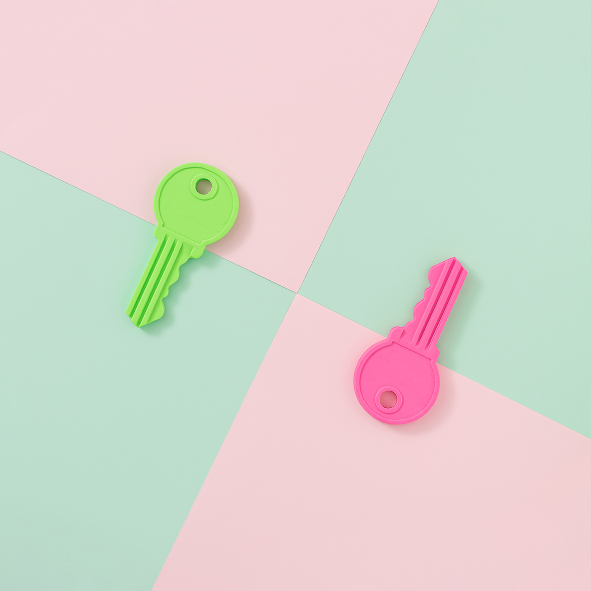 Two keys, one green and one pink, on a green and pink background