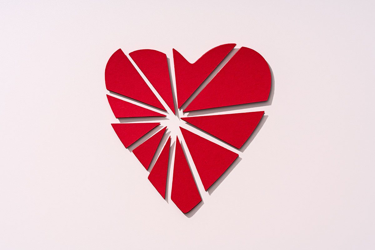 A broken heart made from paper against a beige background