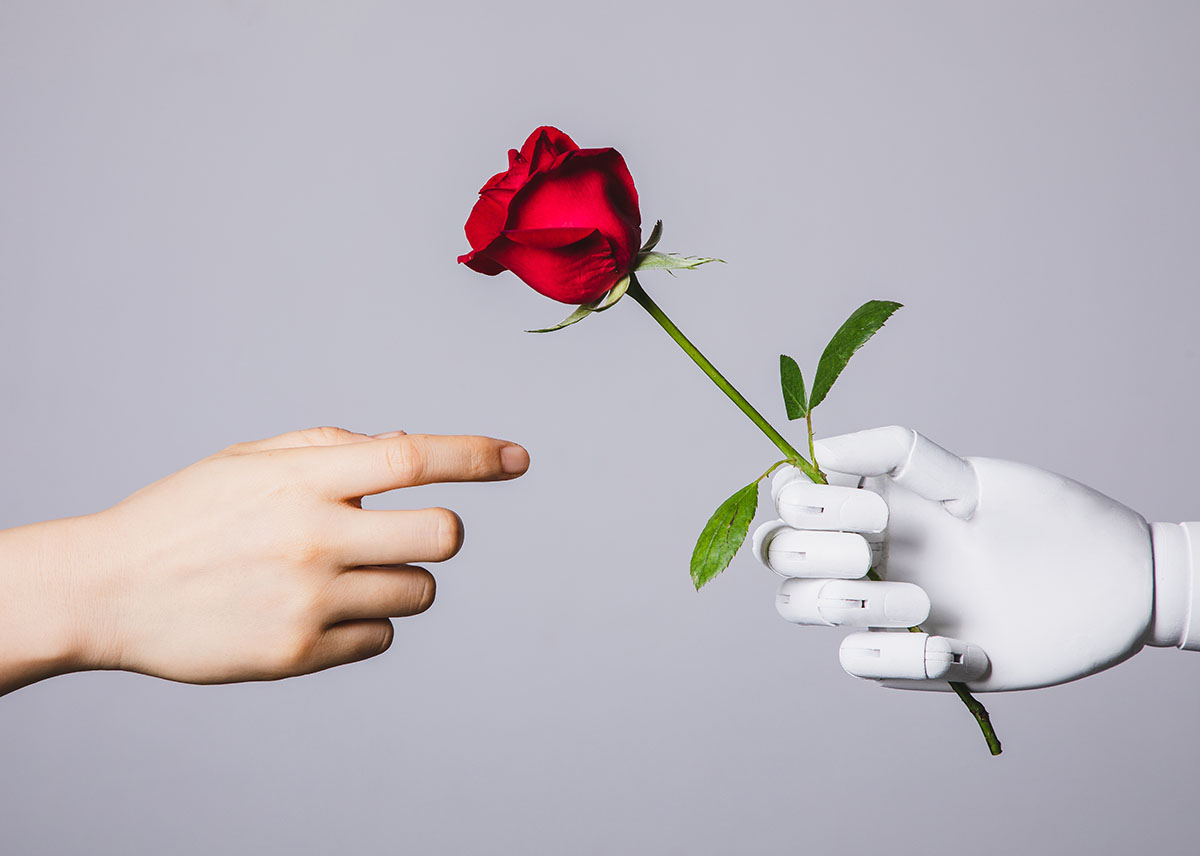 A human hand reaches out to a robot hand holding a red rose
