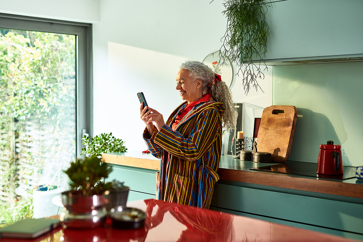 A woman is using her mobile phone, smiling