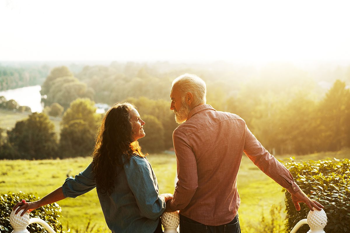 A middle-aged couple looking at each other fondly at sunset in an outdoor setting