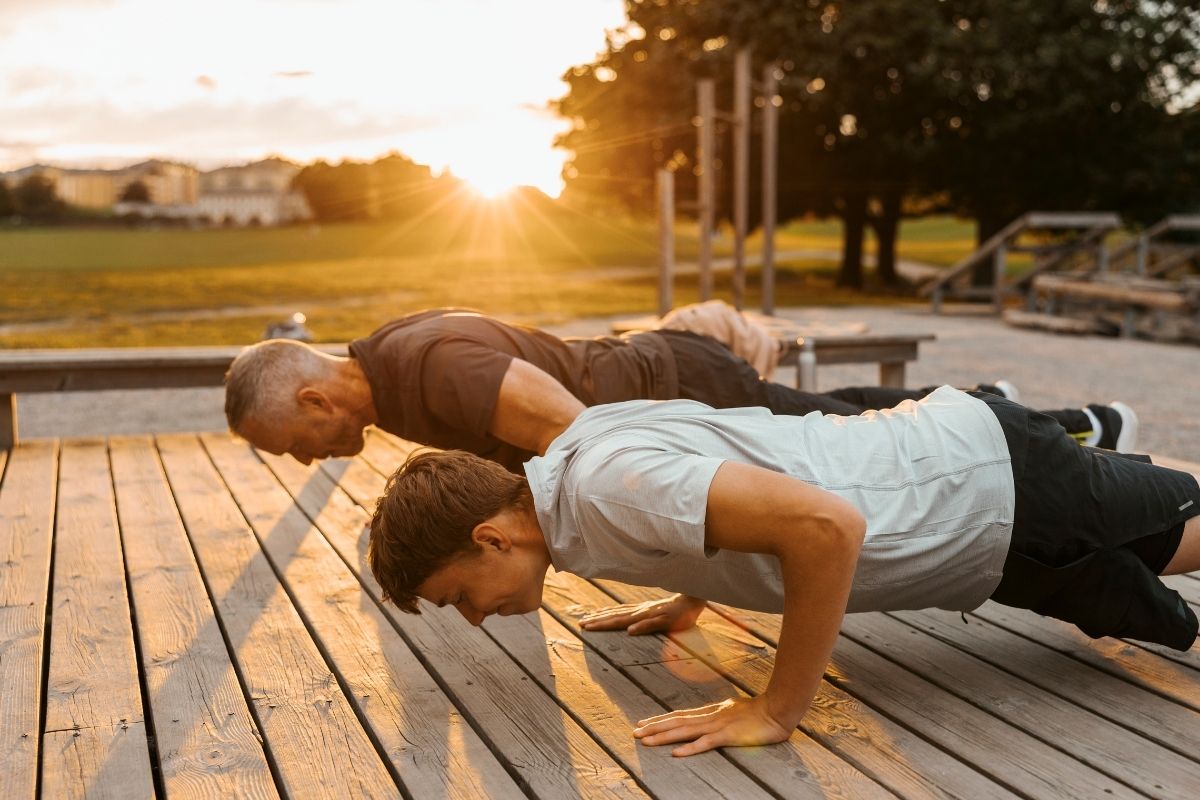 Two men doing push ups outside at sunset