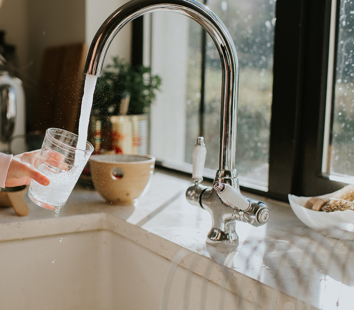 A person fills up a glass of water from a tap