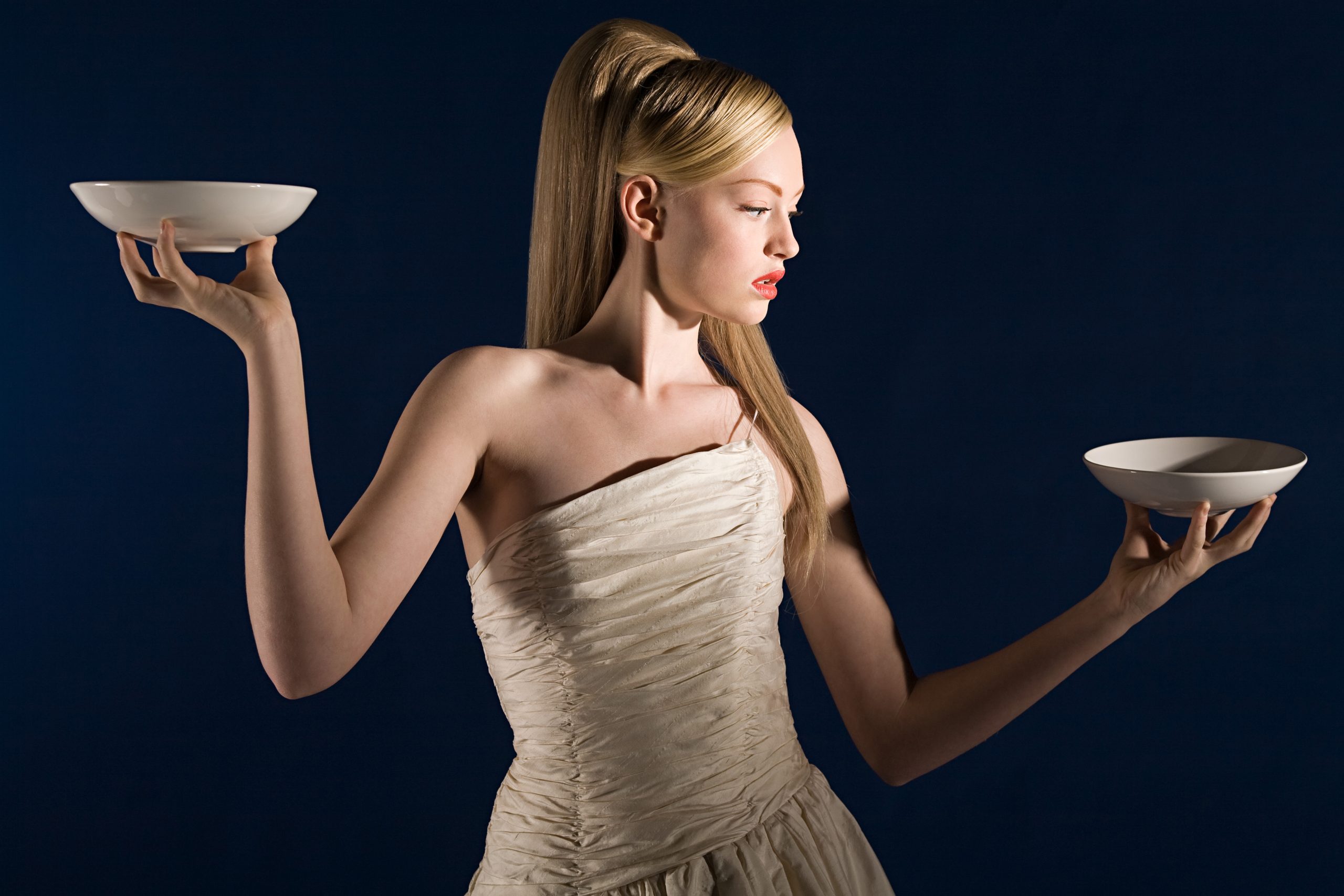 Woman balancing two bowls to recreate the libra sign