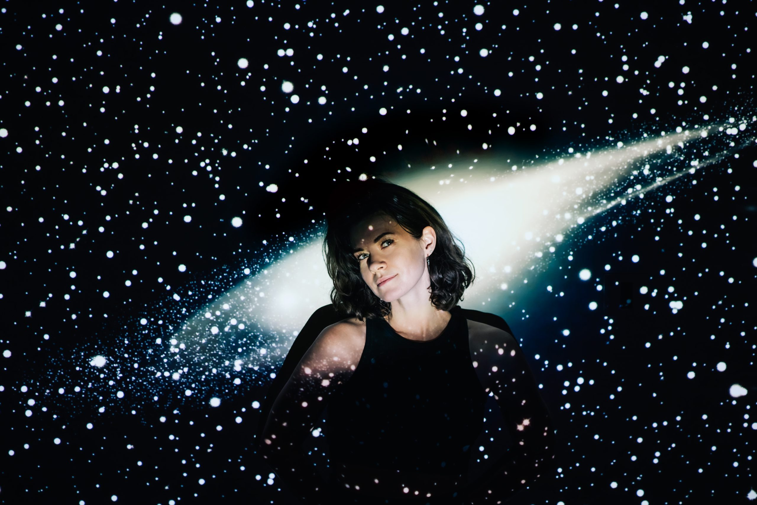 Woman posing in front of projection of space