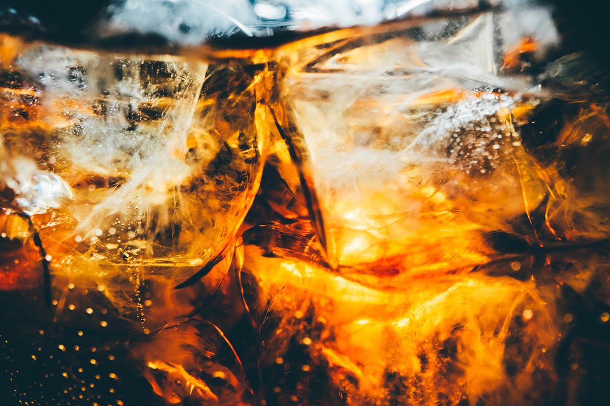 A close-up of a glass of coca-cola with ice cubes
