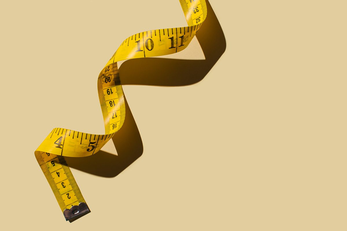 A yellow measuring tape on a beige background