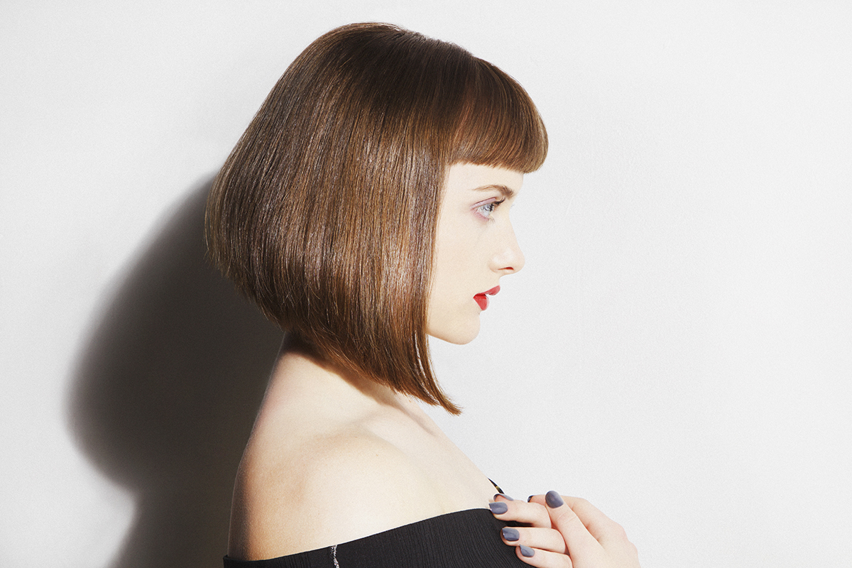 The side profile of a woman with a stylish bob against a white background