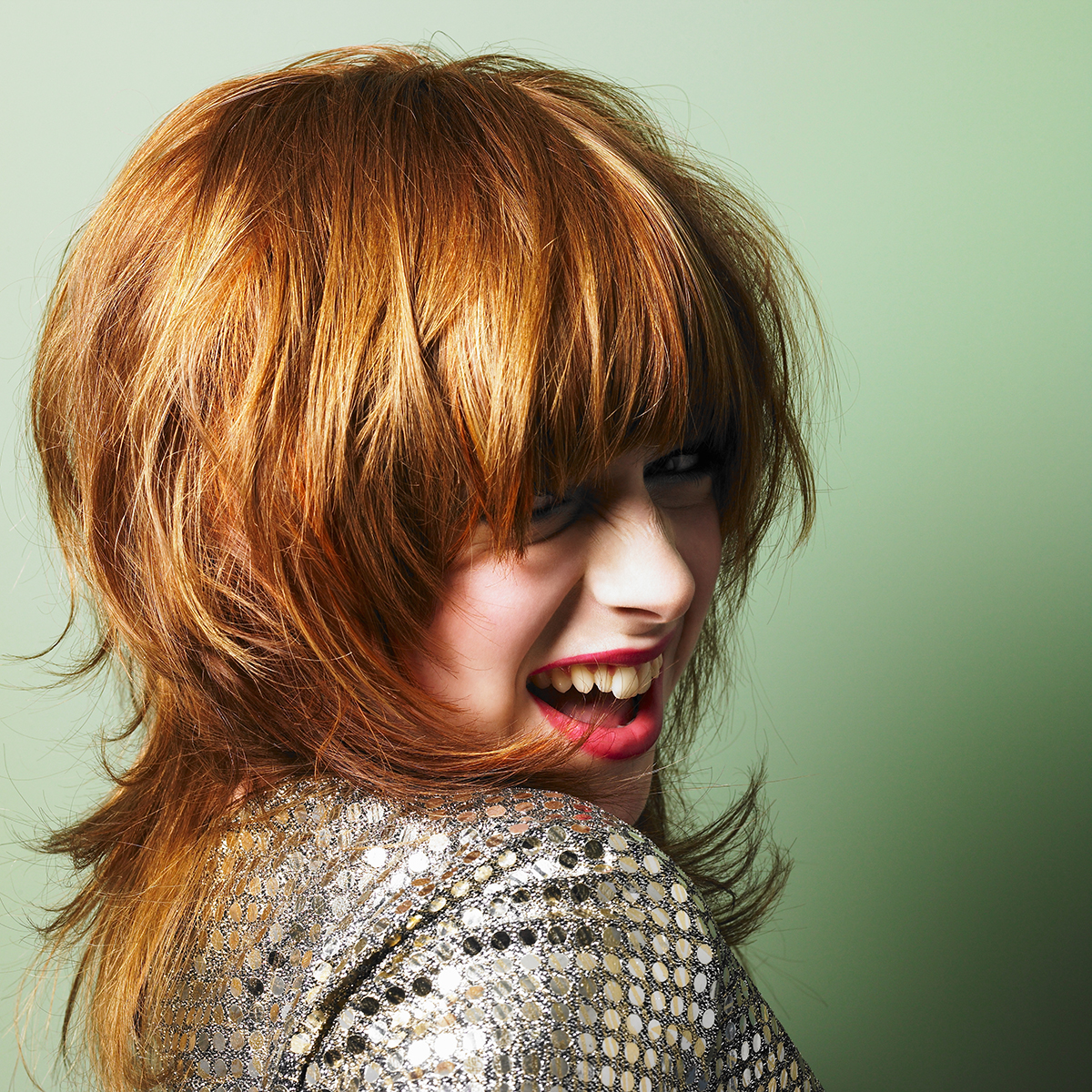 A smiling woman with a shag haircut against a green background