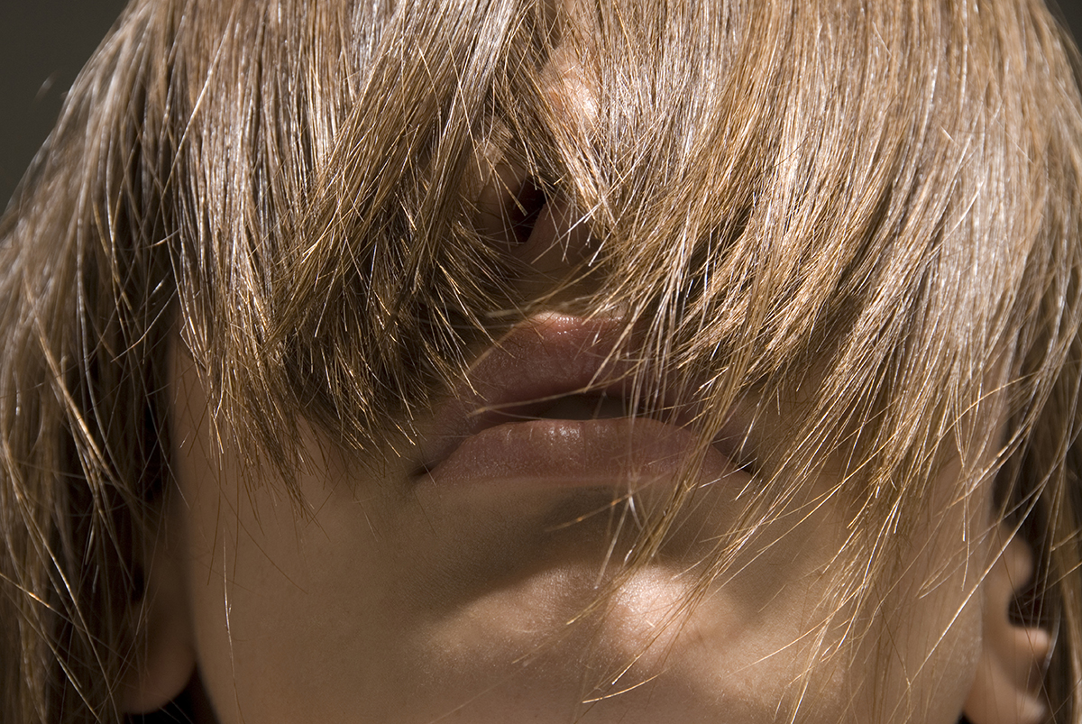 A close-up of a woman with a heavy fringe covering her eyes