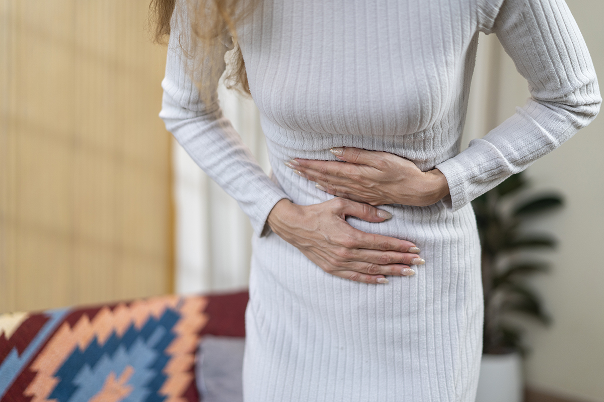 A cropped shot of a woman clutching her stomach