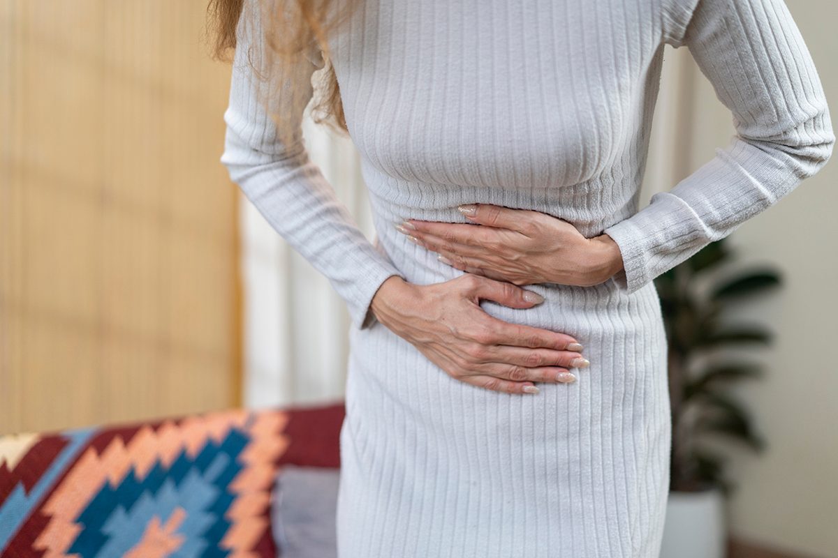 A cropped shot of a woman clutching her stomach