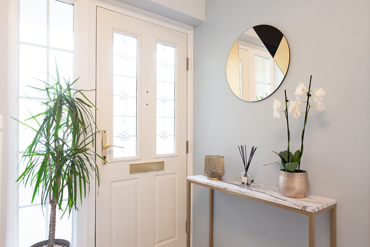 A small hallway painted grey features a gold and marble console table.