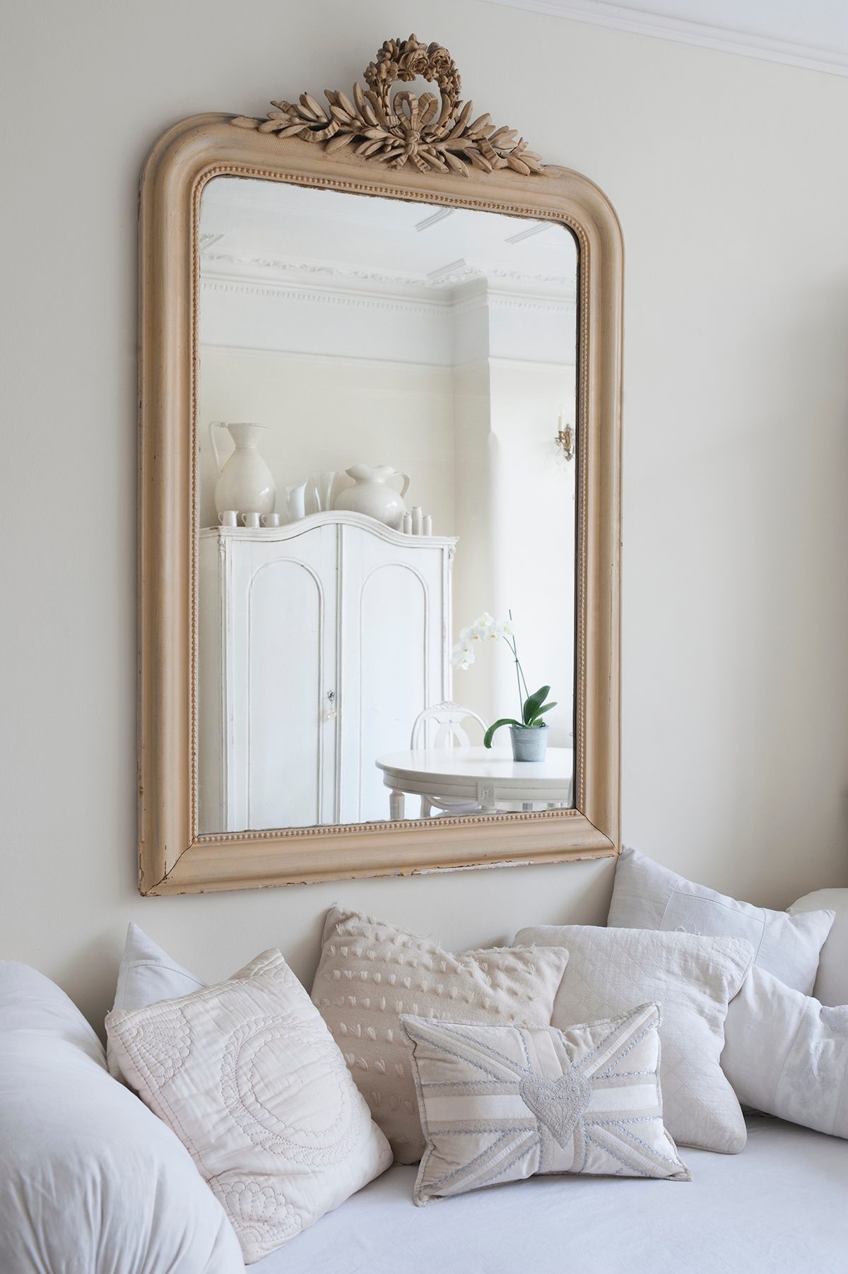 Framed mirror above a bed with cushions.