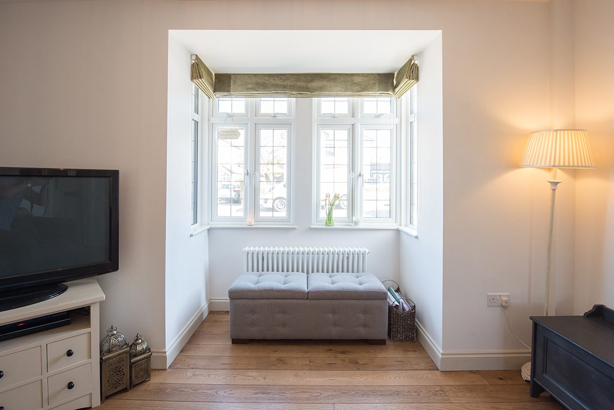 A view of an ottoman bench under a leaded window in a living room.