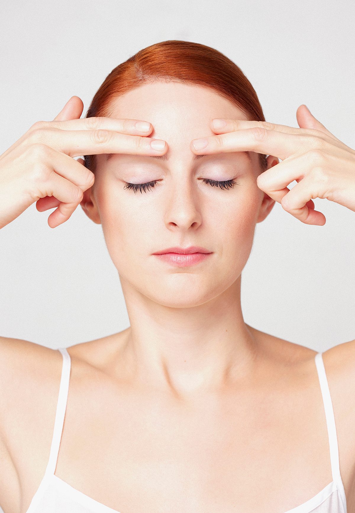 A woman pressing her fingertips to her forehead