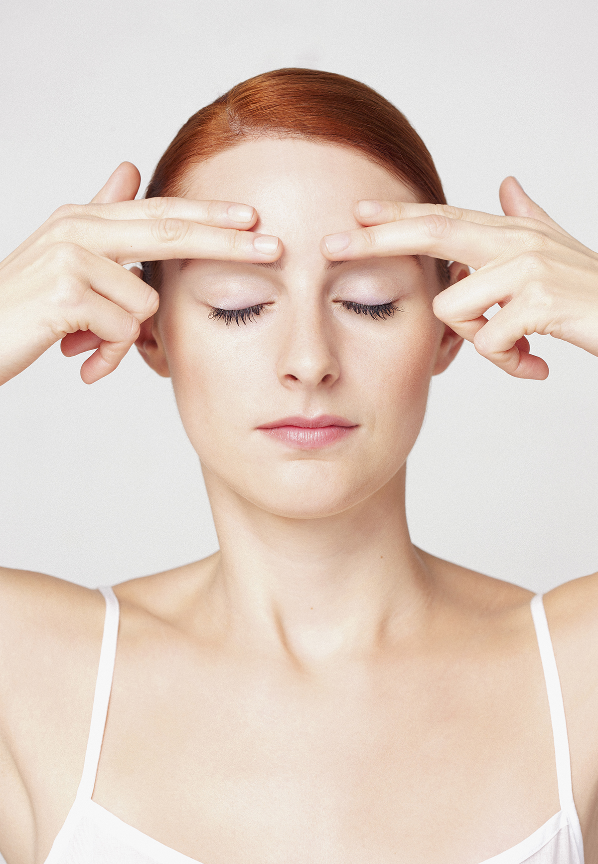 A woman pressing her fingertips to her forehead