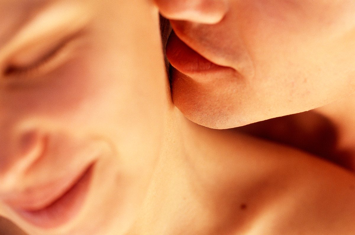A close-up of a man caressing a woman's neck