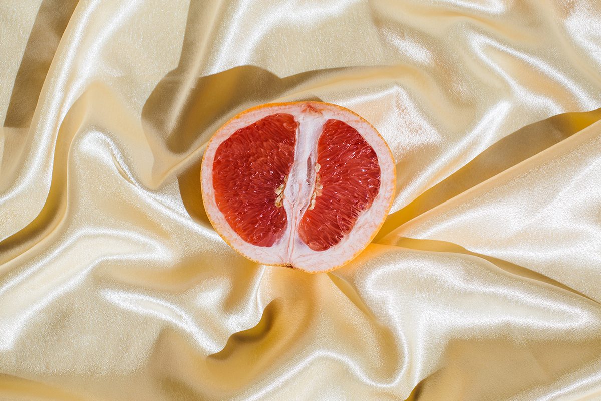 Half of a grapefruit on a crumpled, cream silk sheet