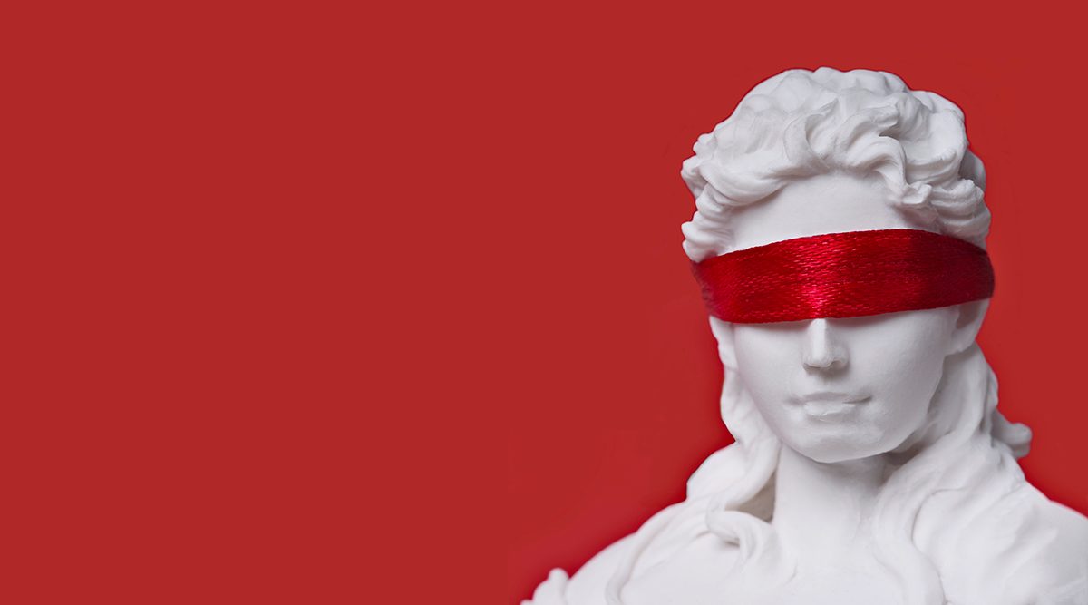 A statue wearing a red blindfold against a red background
