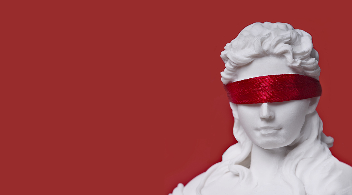 A statue wearing a red blindfold against a red background