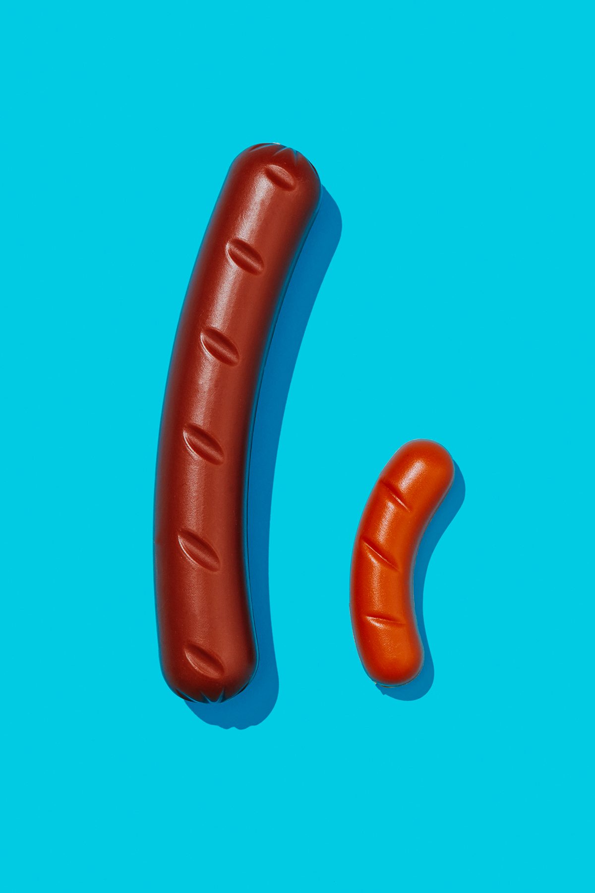 Two different-sized fake sausages on a blue background