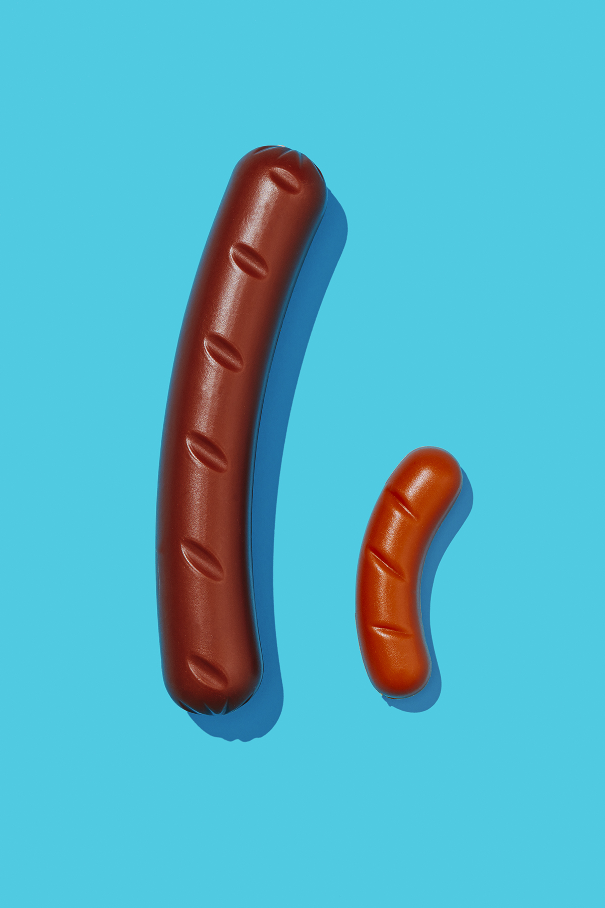 Two different-sized fake sausages on a blue background