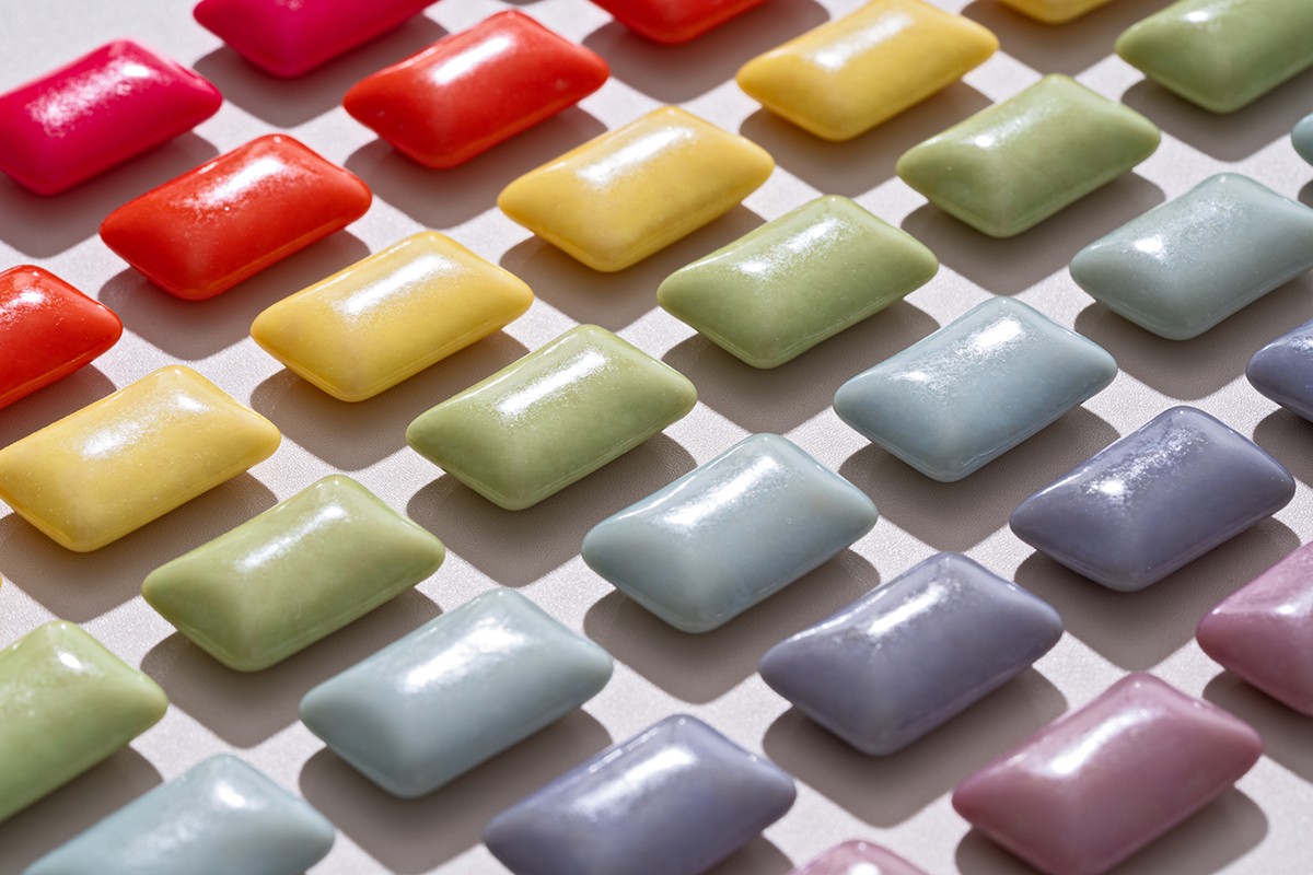 Chewing gums in different colours are arranged neatly in lines.