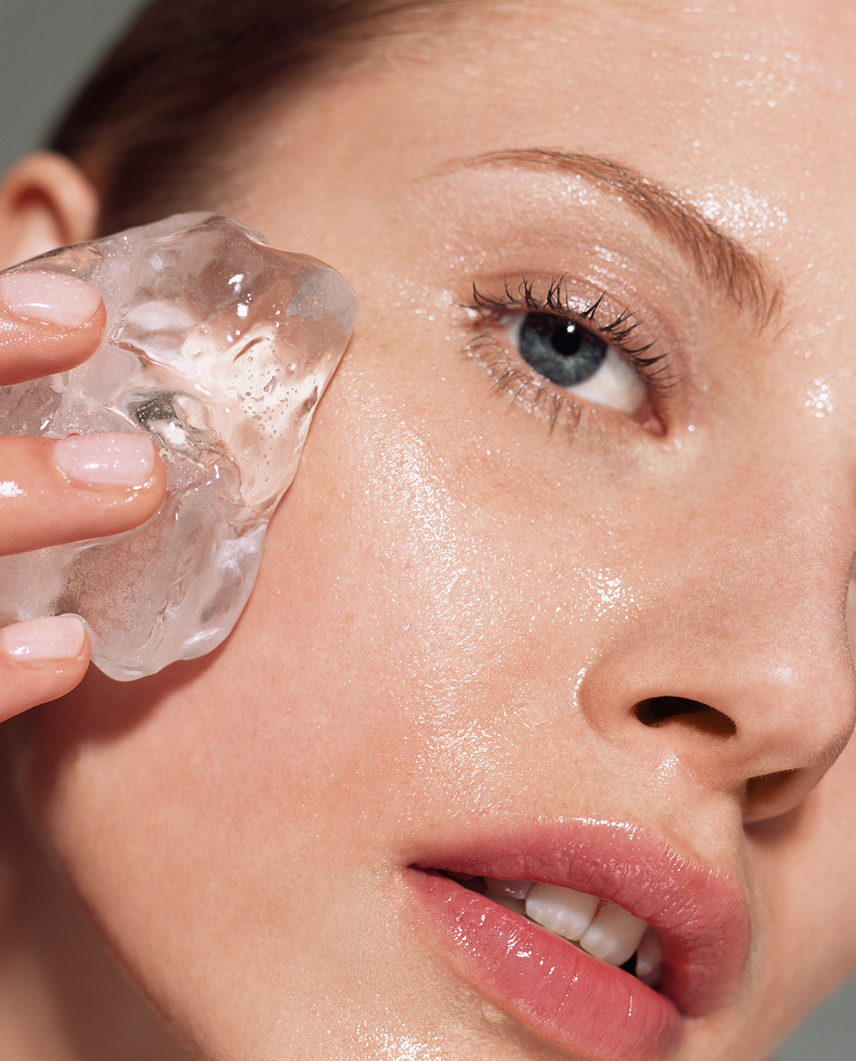 A woman holds a block of ice to her cheek.