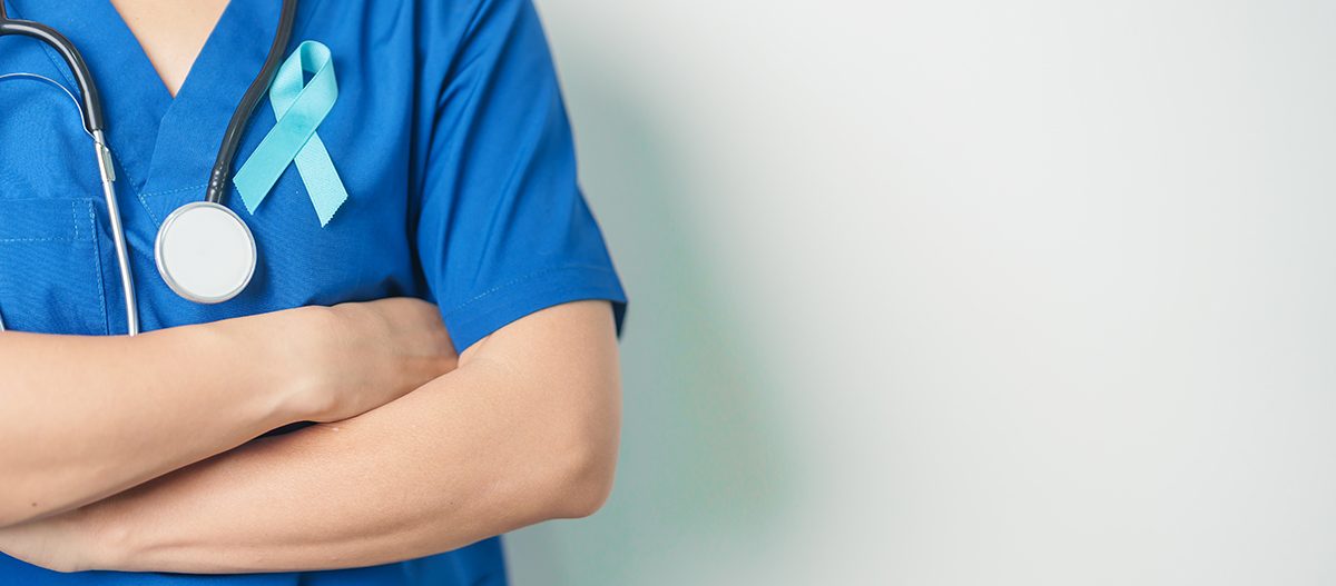 A cropped shot of a doctor wearing scrubs with a prostate cancer awareness ribbon attached