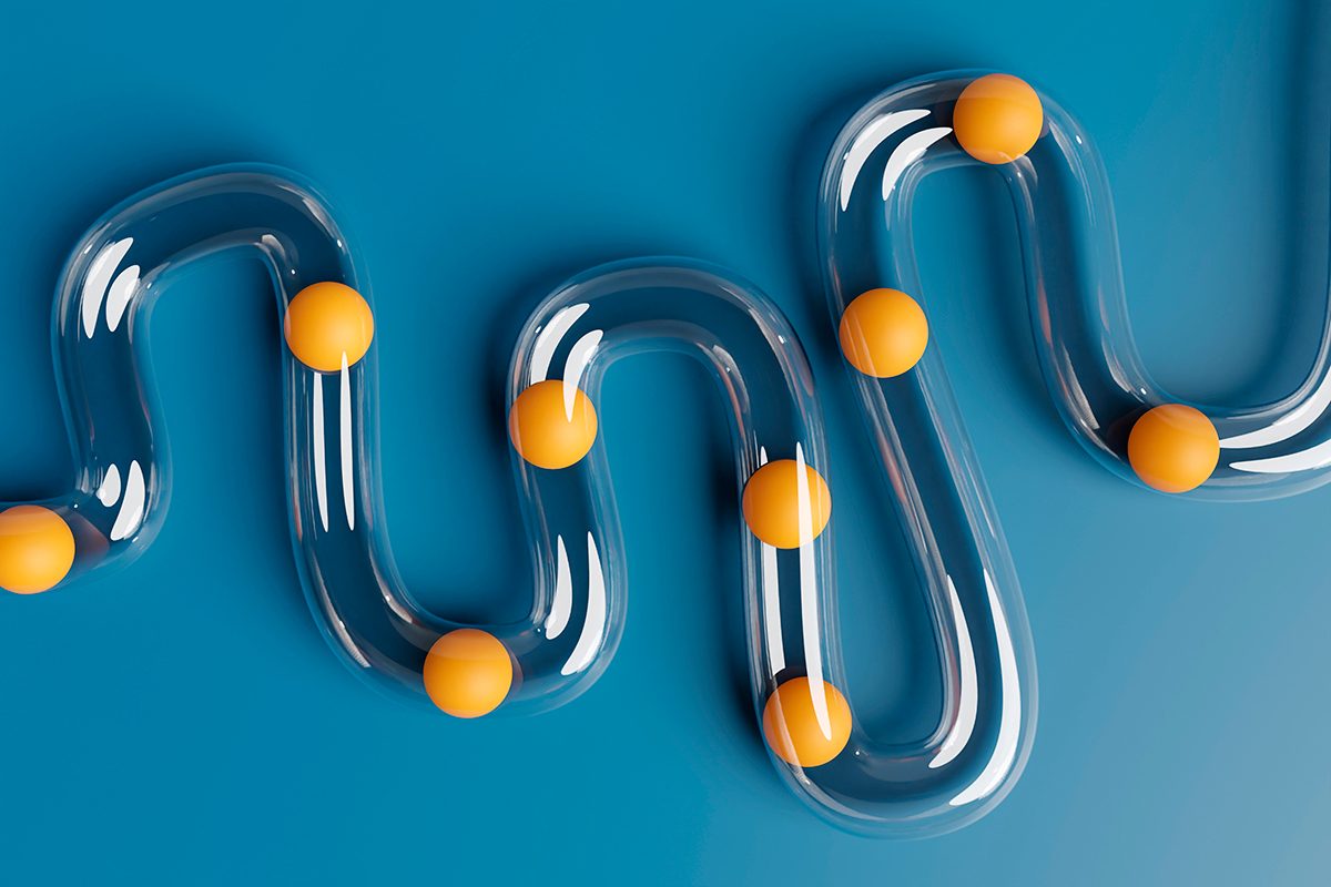 Orange balls are inside transparent plastic tubes on a blue background to represent digestion