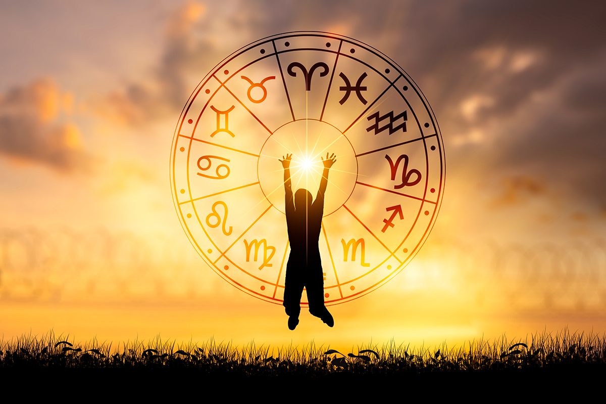 A silhouette jumping in front of a horoscope wheel, set against an outdoor sunset scene