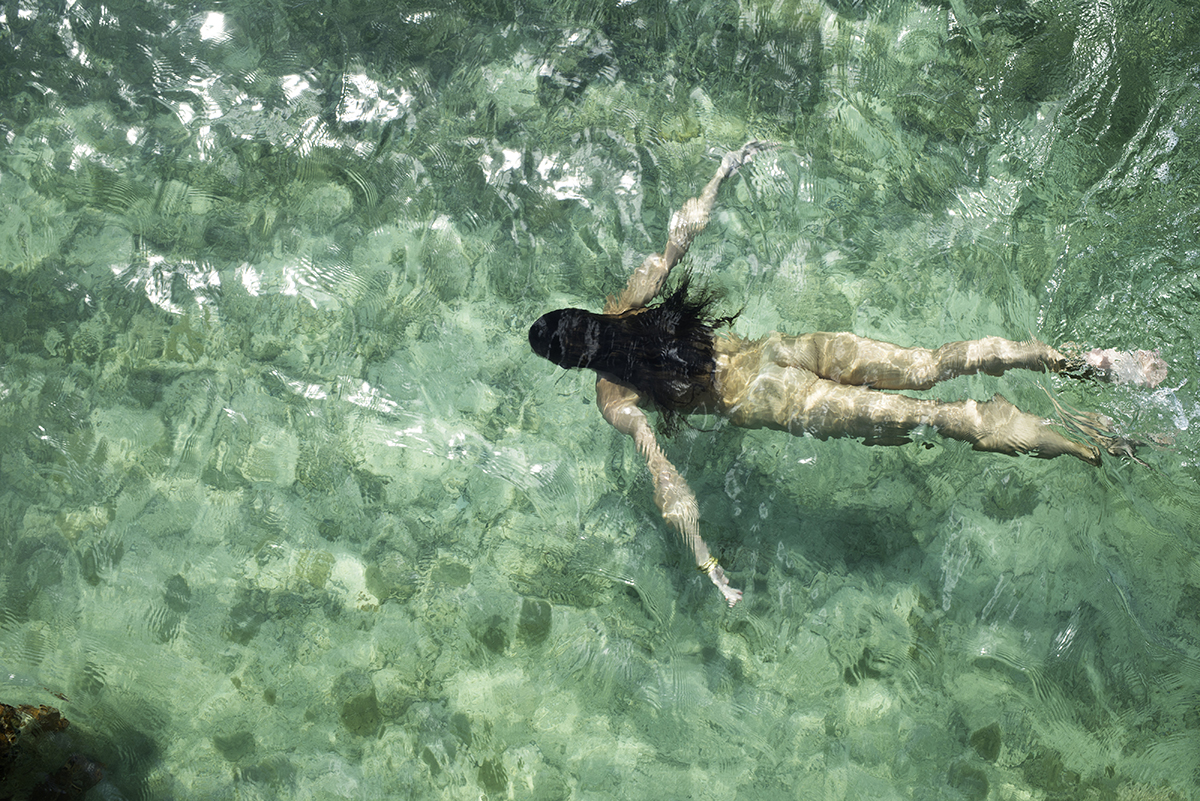 A nude woman swimming in clear water