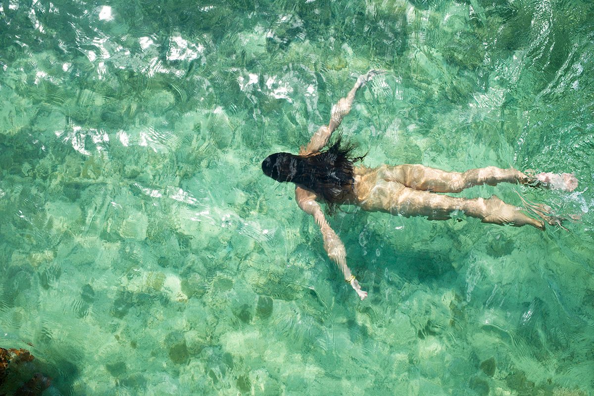 A nude woman swimming in clear water