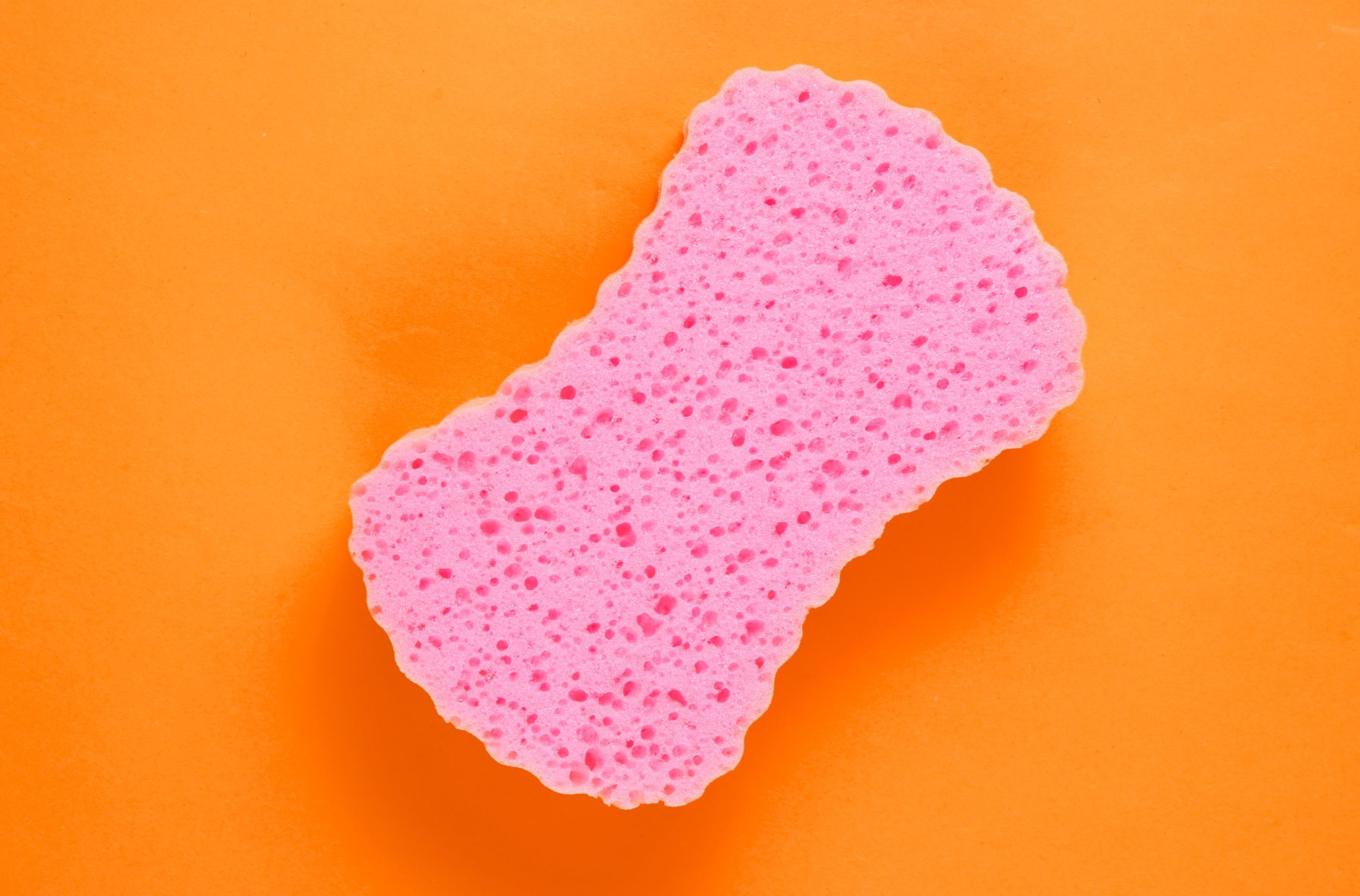 Soft pink bath sponge on orange background. Top view. Minimalism"n&nbsp;"n