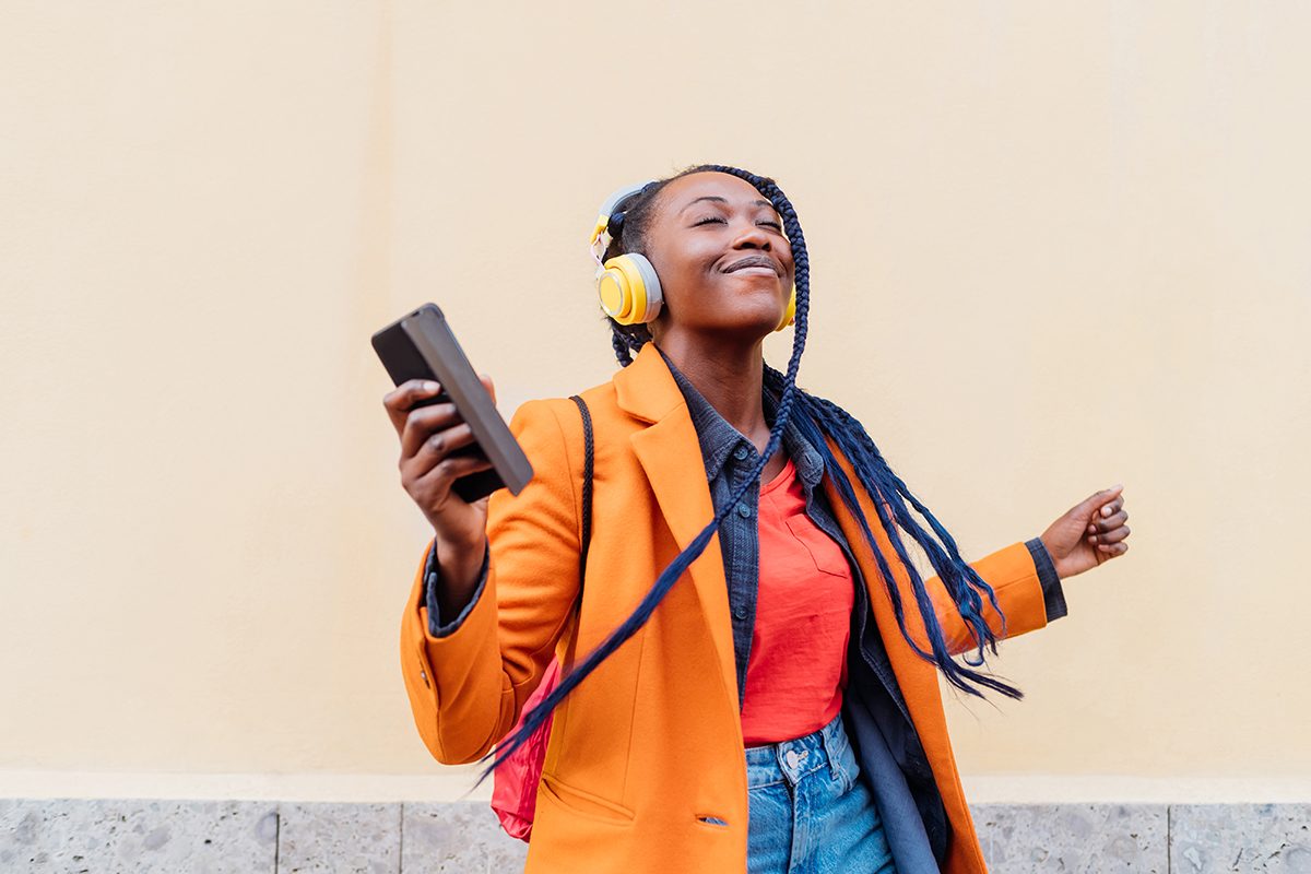 A woman listening to music through headphones outdoors