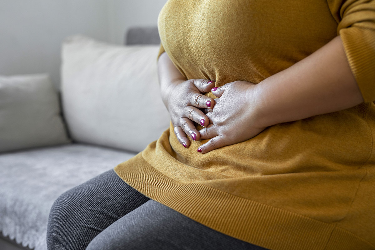 A woman has her hands on her stomach, signalling discomfort