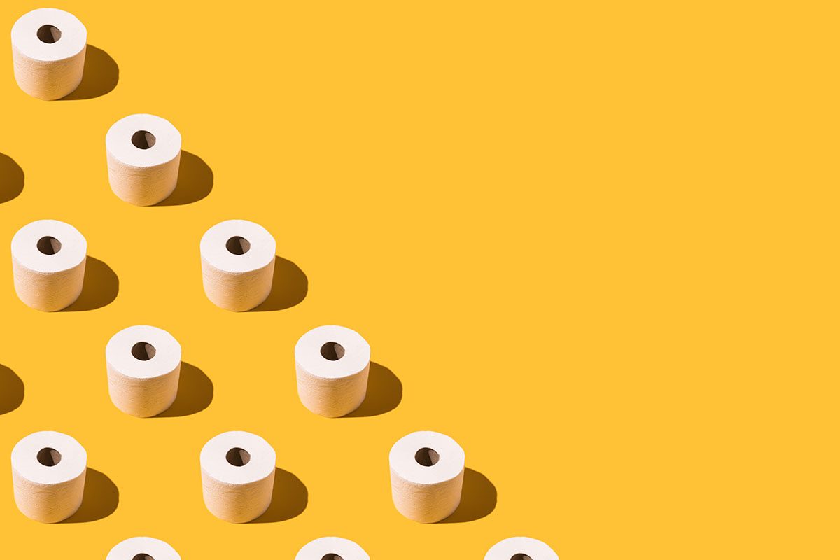 White toilet rolls are arranged in three diagonal rows on a yellow background
