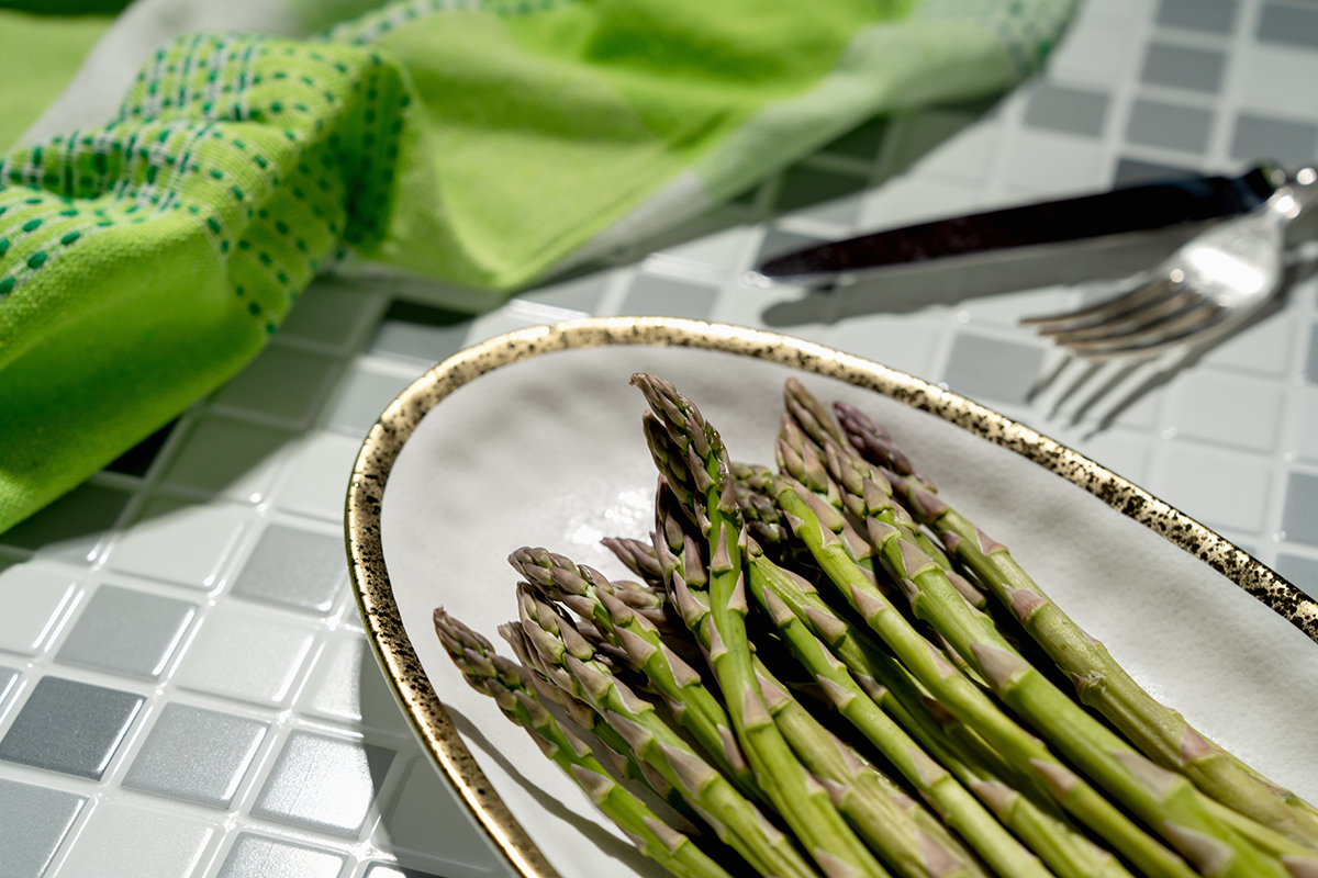 A plate of asparagus on a tiled kitchen counter