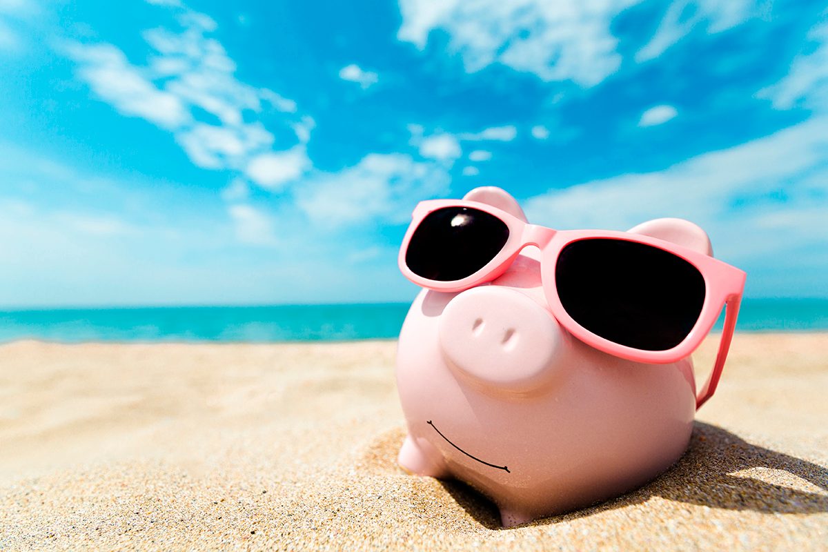 A piggy bank wearing sunglasses on a sandy beach