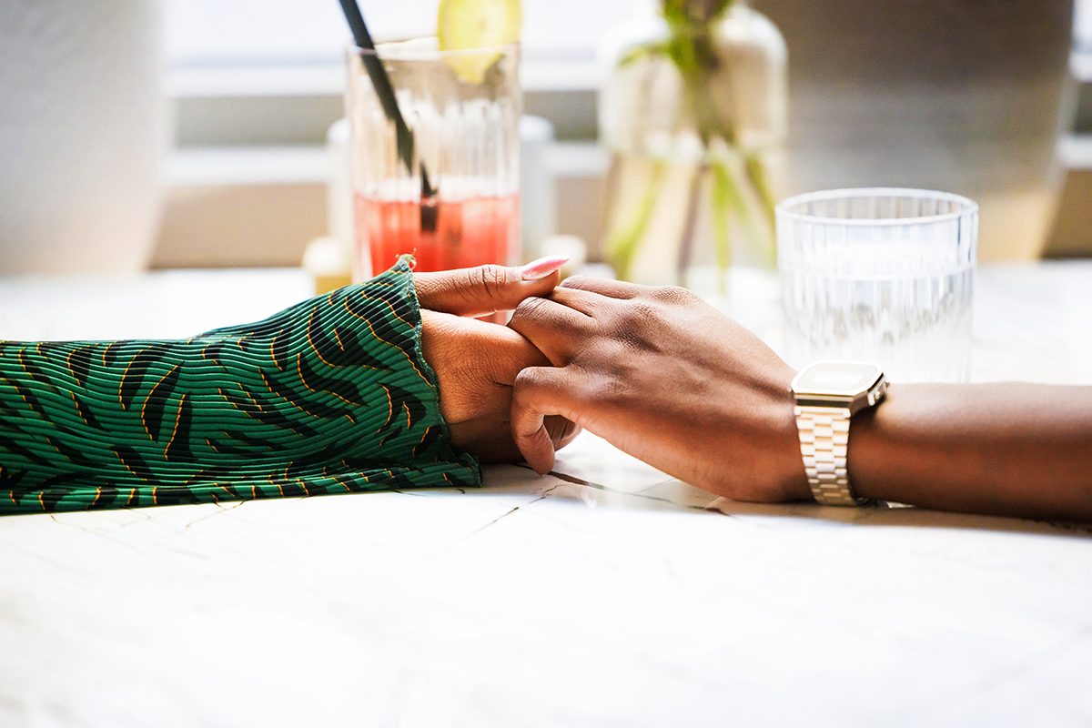 A close-up of two people holding hands across a table