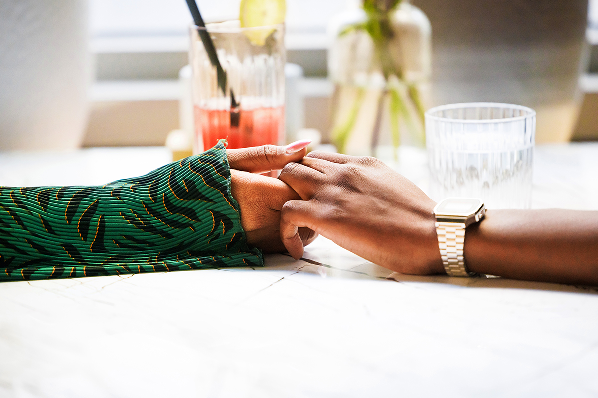 A close-up of two people holding hands across a table