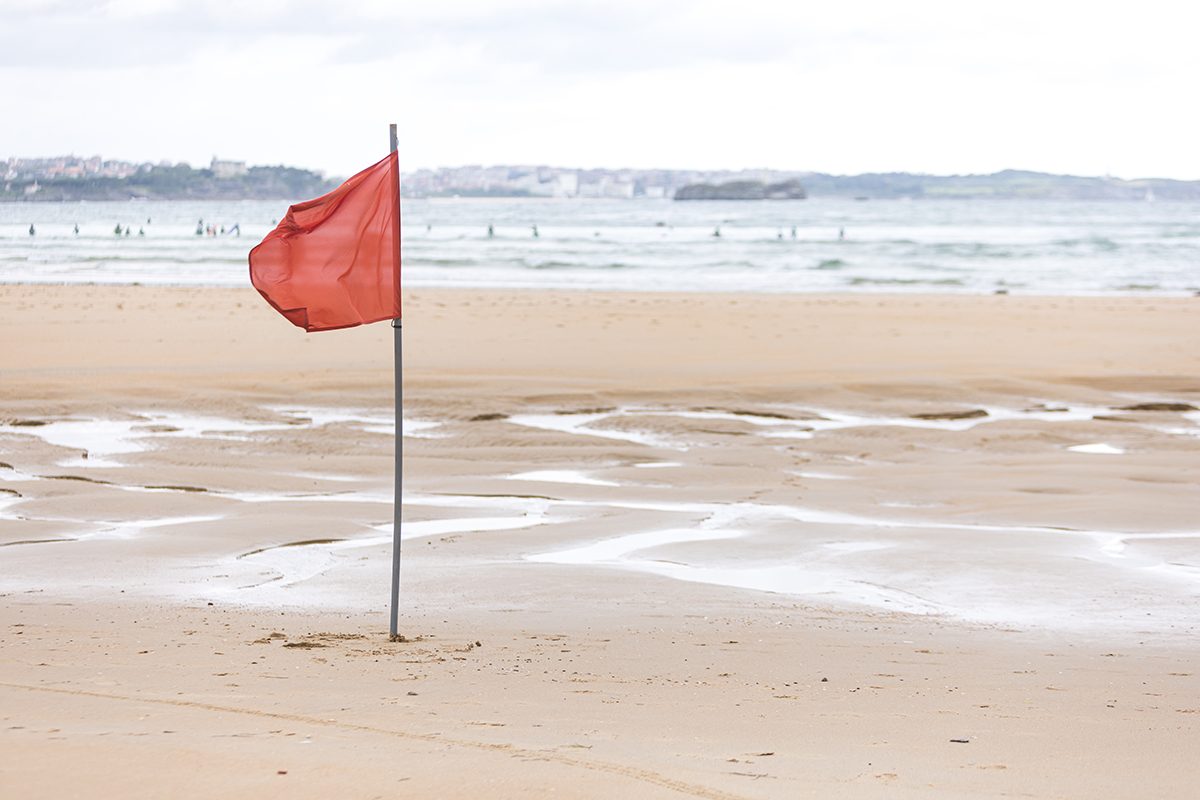 A red flag waving in the breeze on the beach