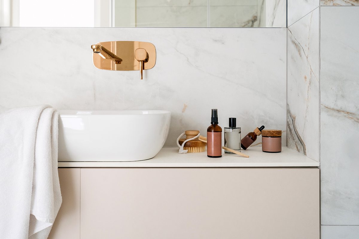 Cosmetic products are displayed on a bathroom countertop, next to the sink