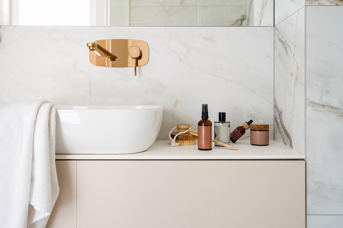 Cosmetic products are displayed on a bathroom countertop, next to the sink