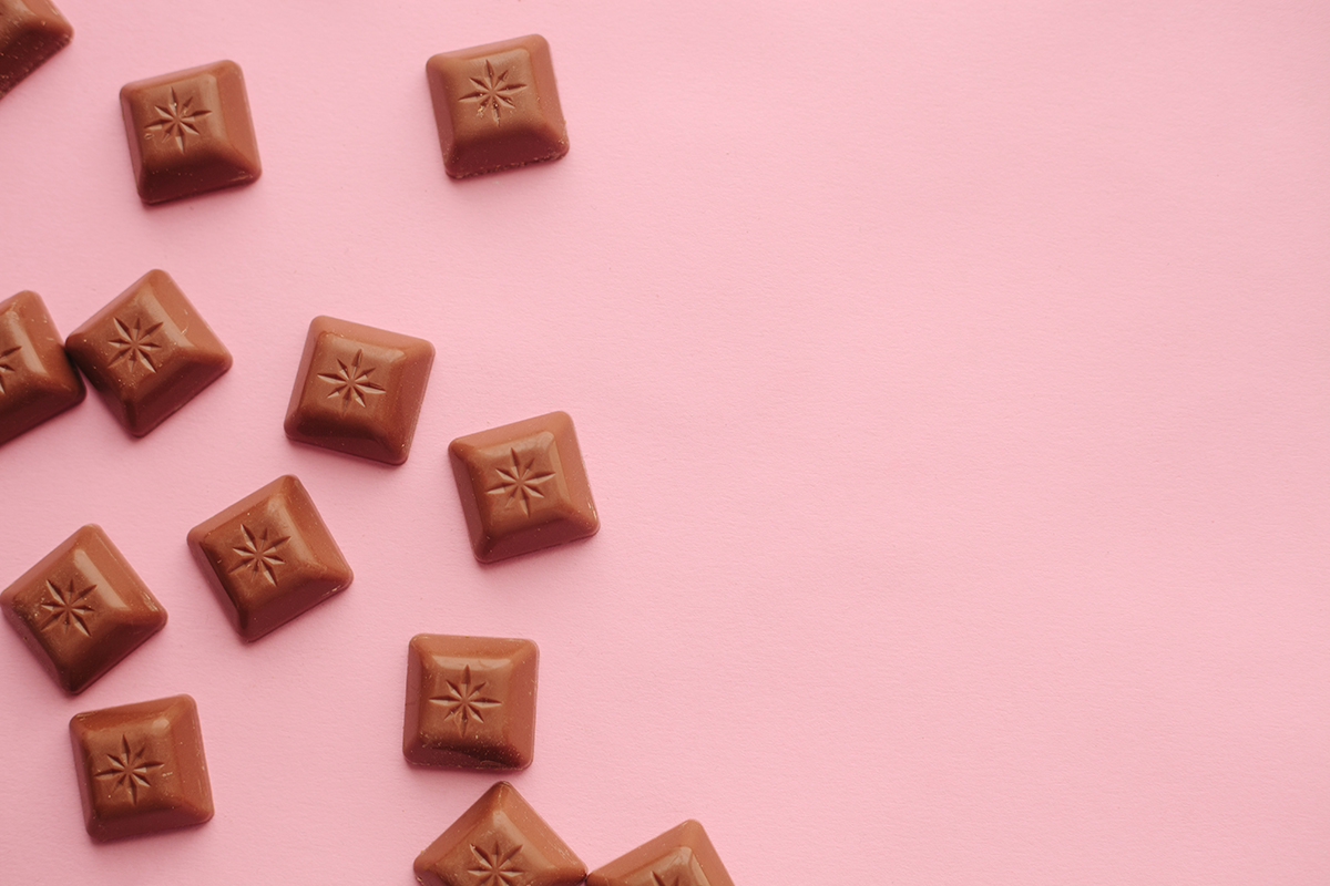 Squares of milk chocolate on a pink background