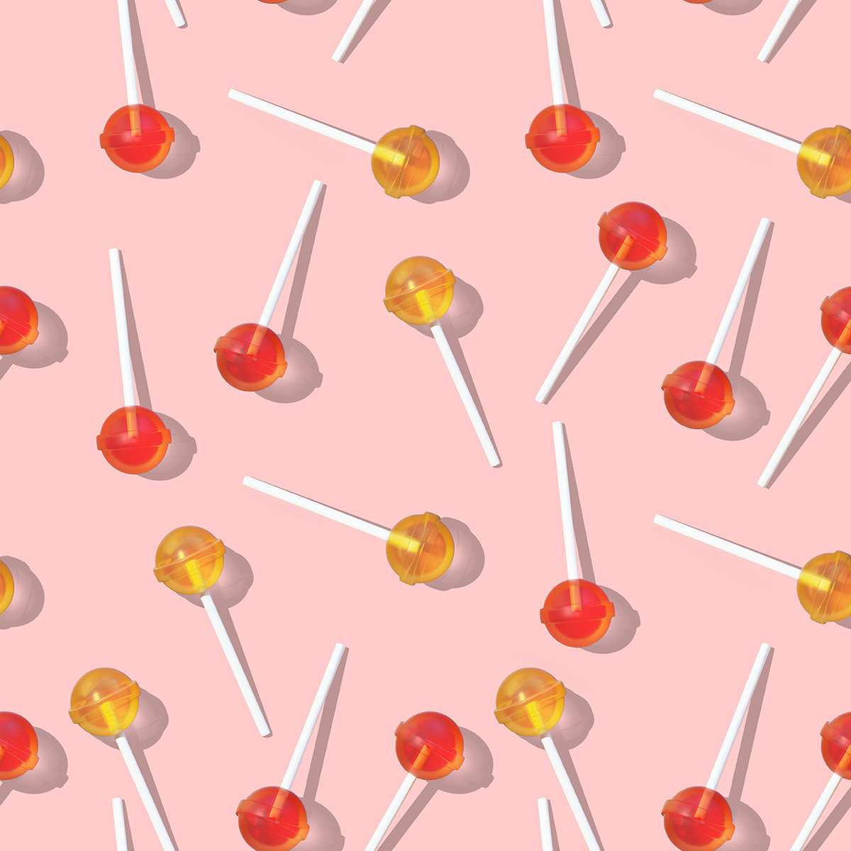 A pattern of orange and yellow lollipops on a pink background