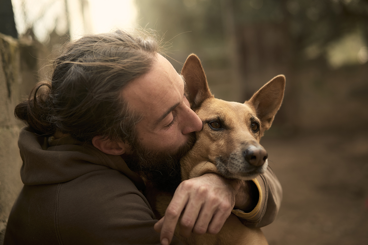 A man kissing his dog's face 