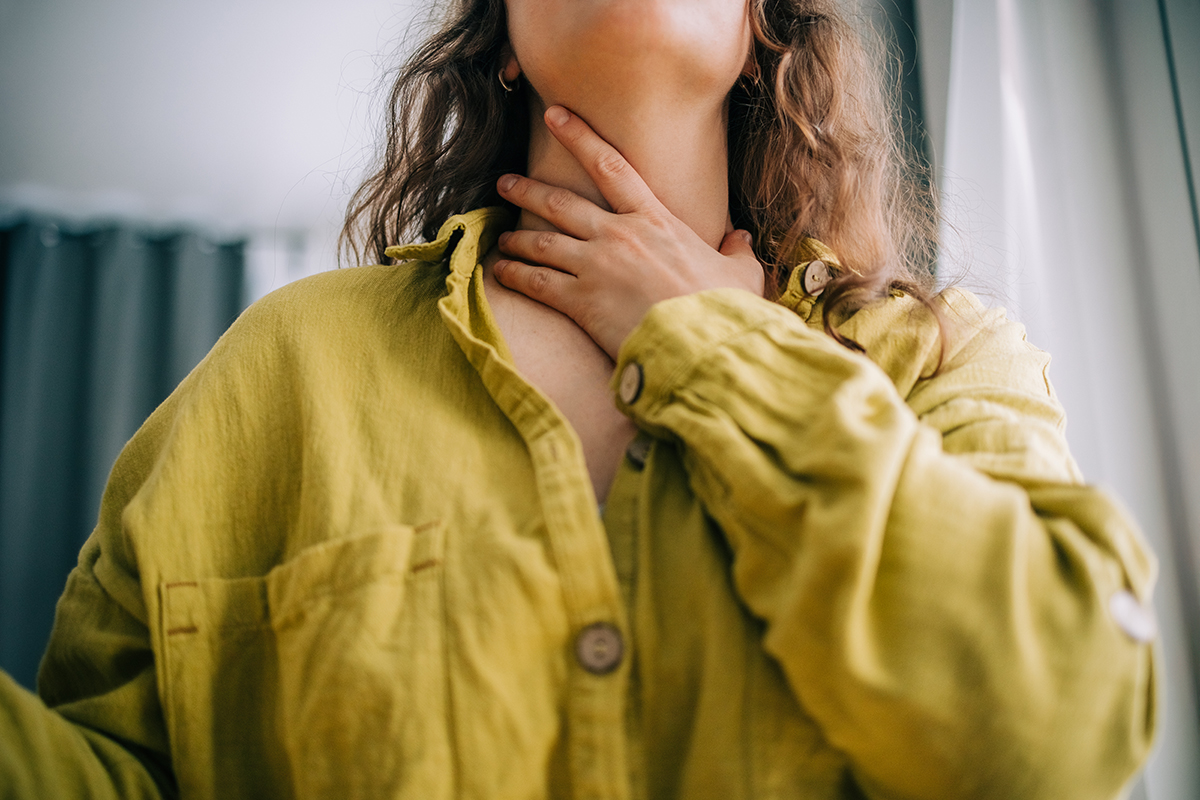 A close-up of a woman holding her neck