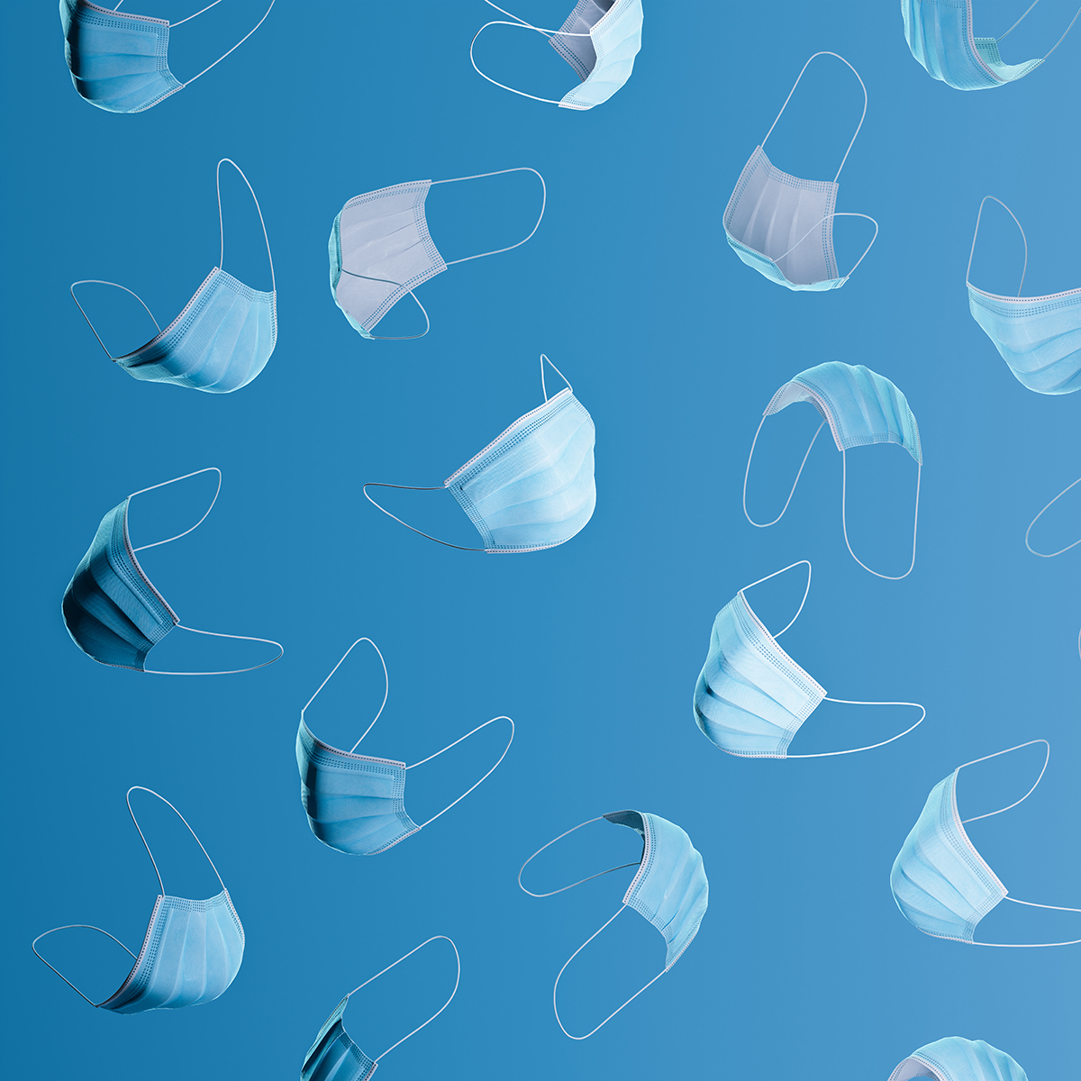 A pattern of medical face masks arranged on a blue background